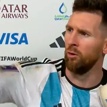 Lionel Messi in Argentina jersey at FIFA World Cup press conference with sponsor logos behind him