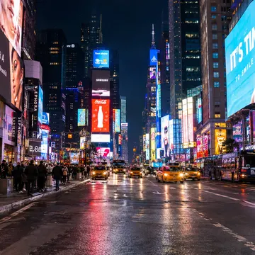 Times Square at night with bright billboards taxis and crowds on wet streets