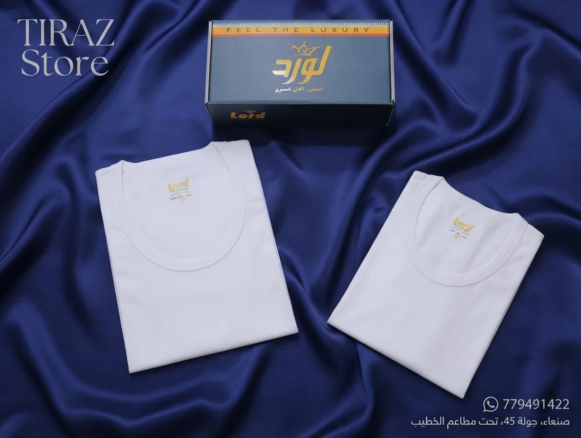 Two white folded t-shirts with gold logos on blue satin fabric with branded packaging nearby