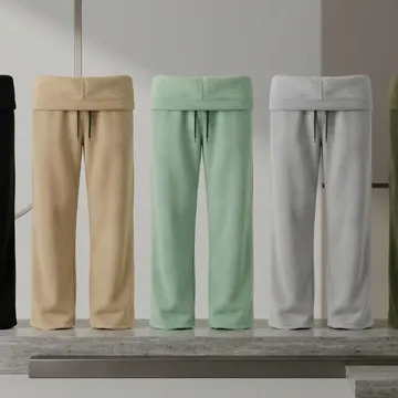 Five colored fleece sweatpants displayed on a concrete platform in a modern setting