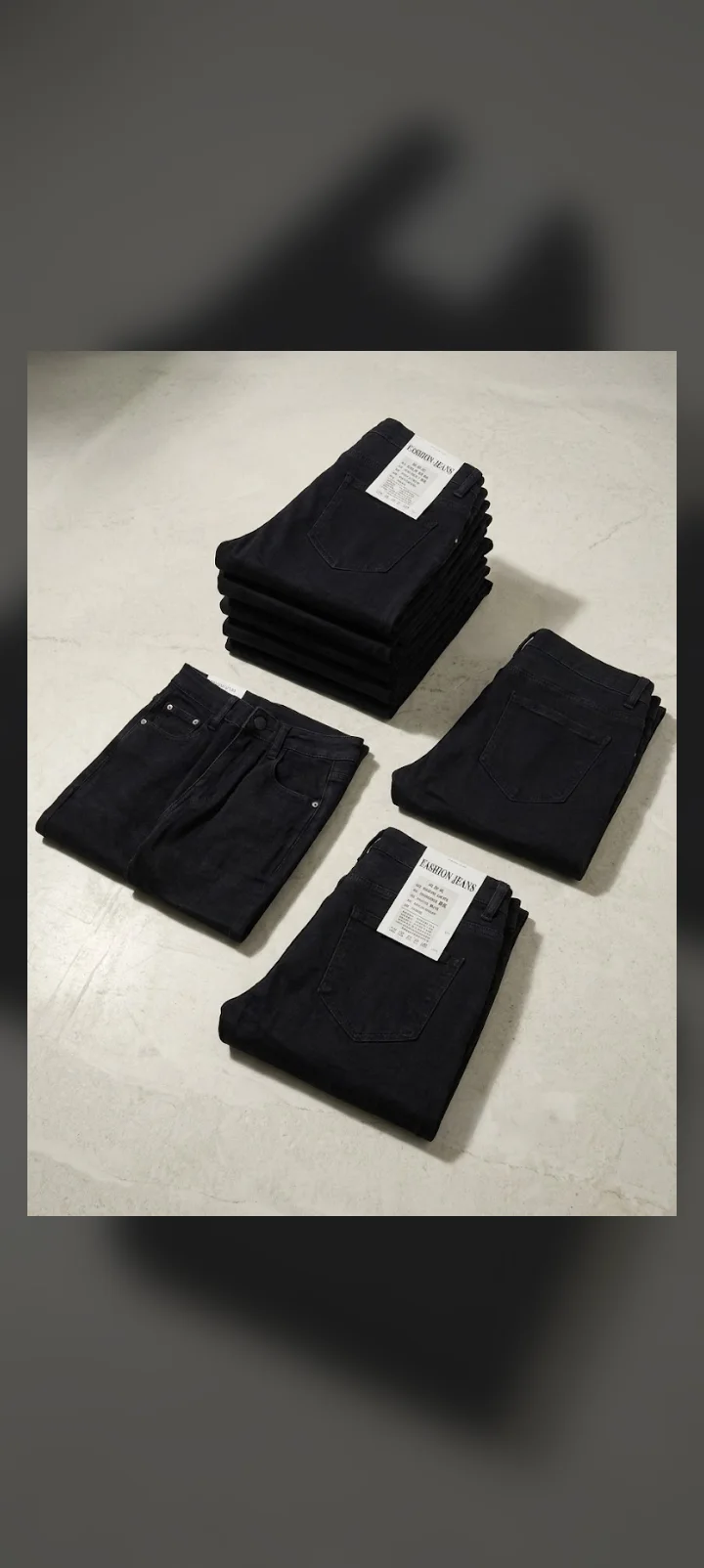 Neatly folded dark denim jeans with tags displayed on a light textured floor