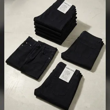 Neatly folded dark denim jeans with tags displayed on a light textured floor