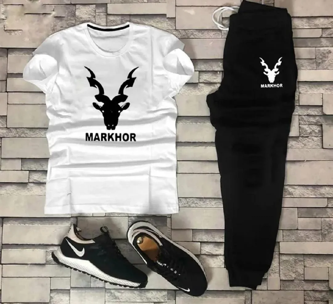 White tshirt black sweatpants and black sneakers with markhor logo on gray brick background