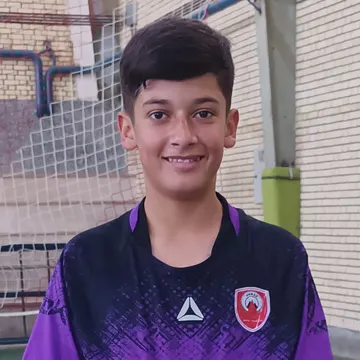 Young boy in purple soccer jersey holding yellow ball indoors
