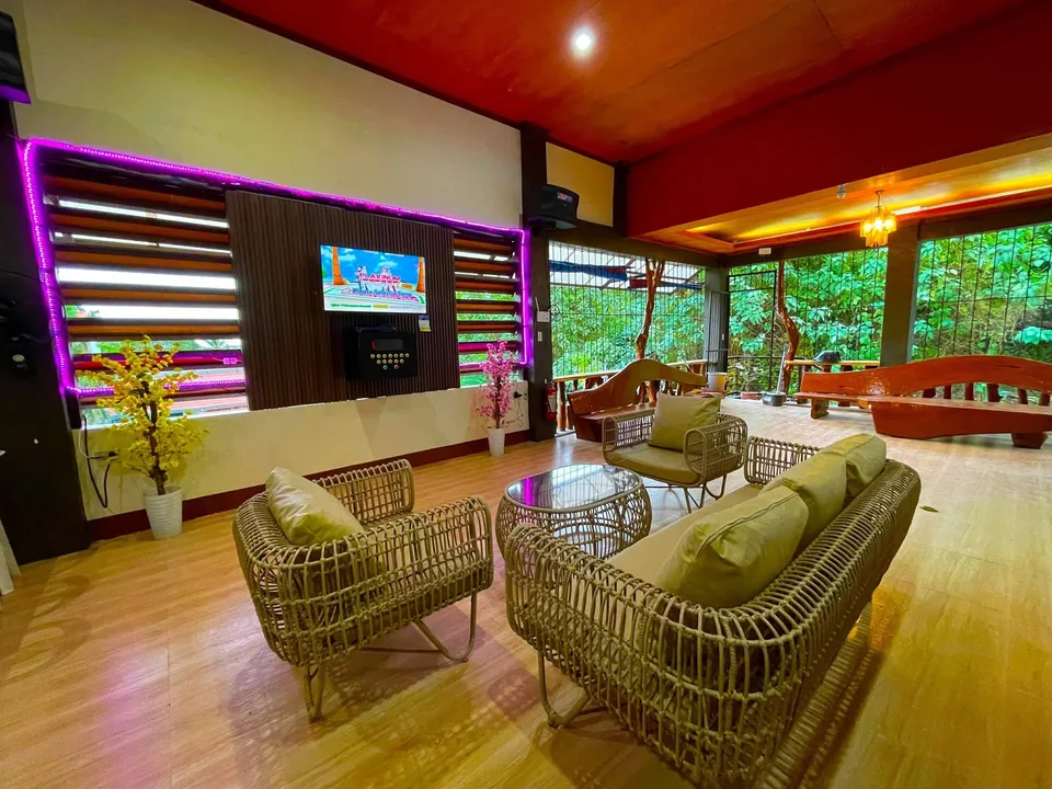 Cozy lounge with wicker furniture and purple neon lights overlooking greenery