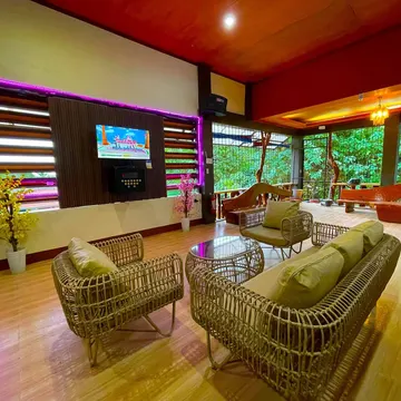 Cozy lounge with wicker furniture and purple neon lights overlooking greenery