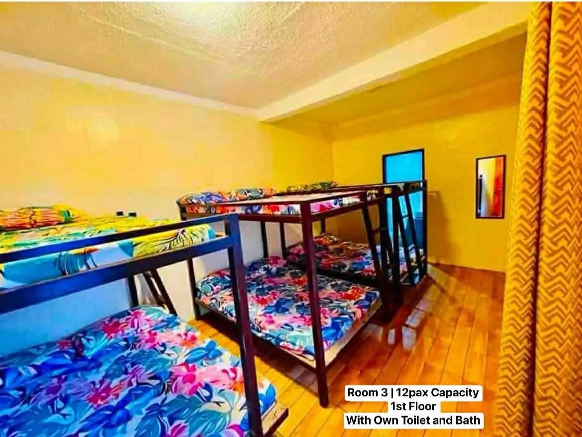 A dorm room with multiple bunk beds and colorful floral bedding on wooden floors
