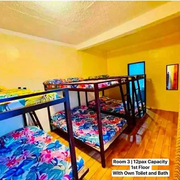 A dorm room with multiple bunk beds and colorful floral bedding on wooden floors