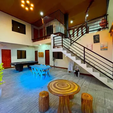 Indoor recreational area with pool table blue chairs wooden table and staircase