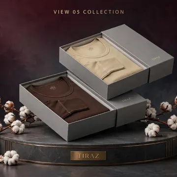 Two gray boxes with folded t-shirts on a marble stand surrounded by cotton branches