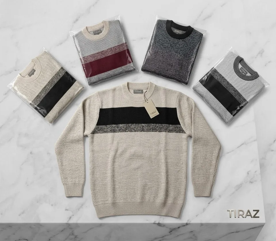 Five packaged sweaters and one beige striped sweater on a marble surface