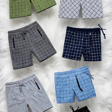 Six pairs of checkered shorts in various colors laid out on a fluffy white rug