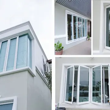 White modern windows on a gray house with glass reflecting sky and greenery